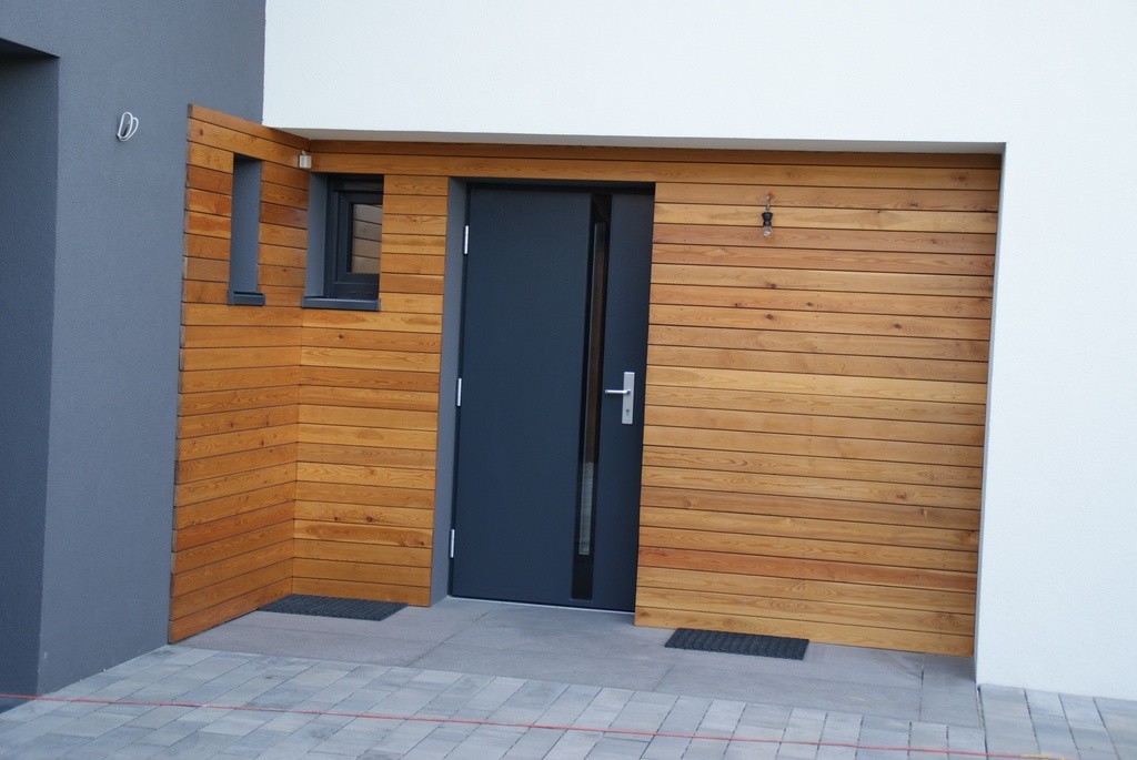 antracytowe drzwi stalowe na tle drewnianych paneli